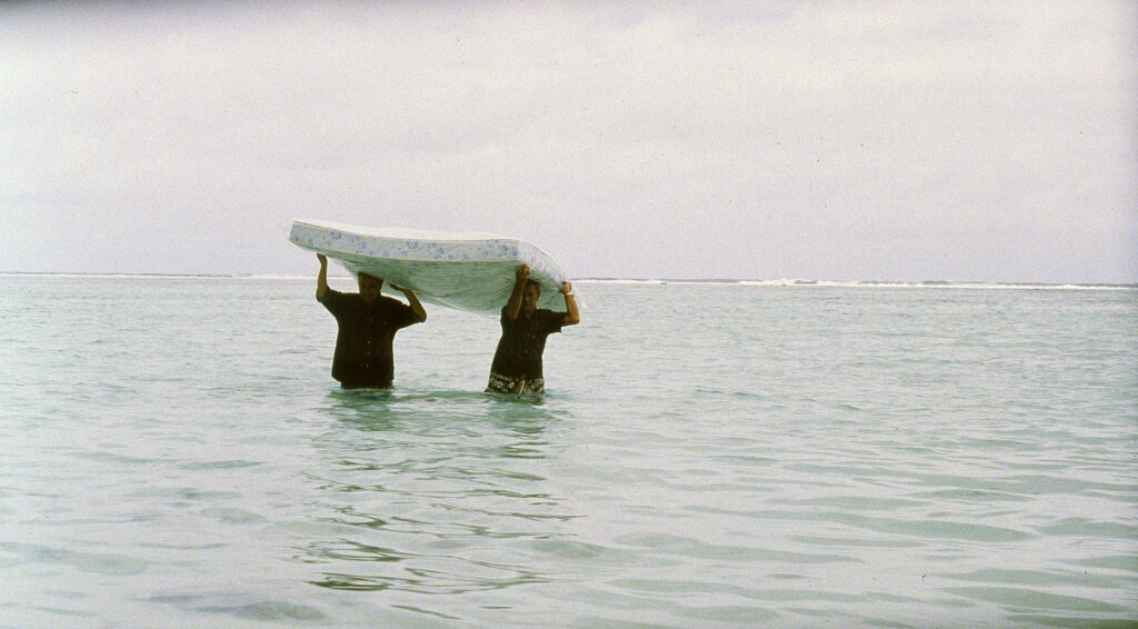 L'intrus (The Intruder) by Claire Denis film still, two men holding mattress over heads in the sea